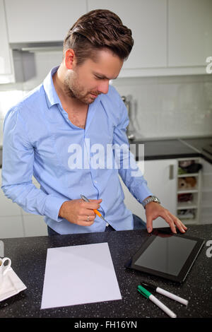 Giovani e diligente uomo al lavoro su tablet Foto Stock