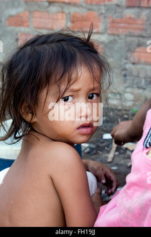 Una giovane ragazza che vivono in condizioni di povertà si trova al di fuori di casa in Kampong Cham, Cambogia. Foto Stock