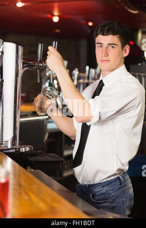 Ritratto di barman holding di vetro al distributore di birra Foto Stock