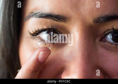 Donna sorridente con una lente a contatto Foto Stock