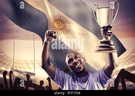 Immagine composita di felice sportivo cercando e rasserenanti tenendo trophy Foto Stock