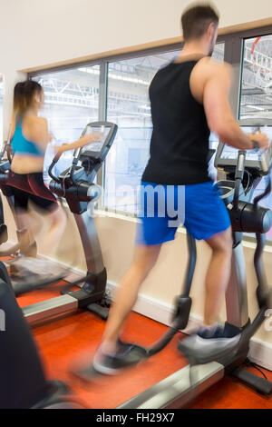 Uomo e donna che utilizza macchine ellipitical Foto Stock