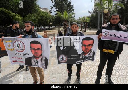 La città di Gaza, Striscia di Gaza, Territori palestinesi. Il 23 febbraio, 2016. Palestinesi tenere manifesti recanti un ritratto del giornalista palestinese Mohammed al-Qiq chi è imprigionato in una prigione israeliana durante una manifestazione di protesta a sostegno del suo sciopero della fame di Gaza City nel febbraio 23, 2016 Credit: Mohammed Asad/immagini APA/ZUMA filo/Alamy Live News Foto Stock