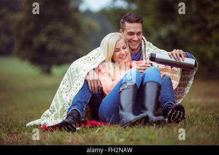 Coppia felice seduto sotto una coperta Foto Stock