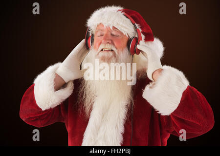 Immagine composita di santa claus gode di alcuni brani musicali Foto Stock