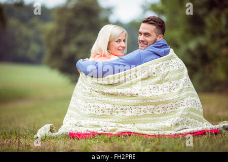 Coppia felice seduto sotto una coperta Foto Stock