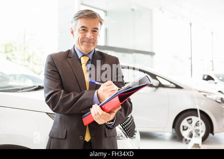 Sorridente venditore di scrittura sulle cartelle di lavoro Foto Stock