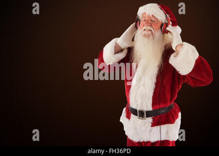 Immagine composita di santa claus gode di alcuni brani musicali Foto Stock