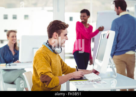 Graphic designer che indossano le cuffie alla scrivania Foto Stock