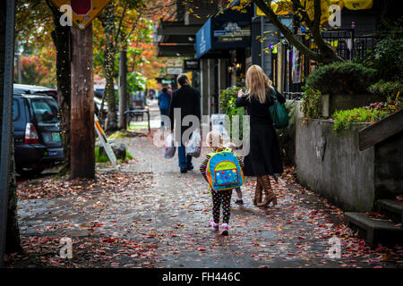 Vista posteriore del schoolgirl camminando con la madre sul marciapiede, Seattle, nello stato di Washington Foto Stock