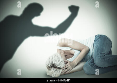 Immagine composita della triste donna bionda sdraiato sul pavimento Foto Stock