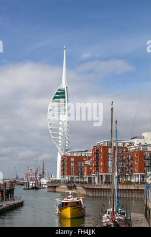 Una barca da pesca si avvicina a un molo nel Dock di campanatura, con Portsmouth Gunwharf Quays e Spinnaker Tower in background. Foto Stock