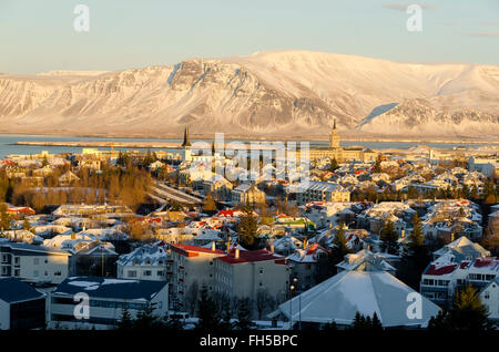 Guardando verso il basso dello skyline della città panoramica di Reykjavic Islanda in inverno con neve e lo sfondo di montagna. Foto Stock