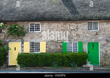 Due tradizionali in pietra costruito cottage con il tetto di paglia con dipinte di verde e giallo porte e persiane in West Lulworth, Dorset, Inghilterra Foto Stock