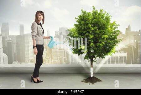 Imprenditrice di irrigazione albero verde su sfondo della città Foto Stock