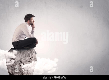 Lavoratore di ufficio seduti sulla cima di una roccia Foto Stock