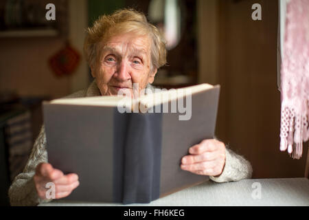 Una donna anziana la lettura di un libro di grandi dimensioni. Foto Stock