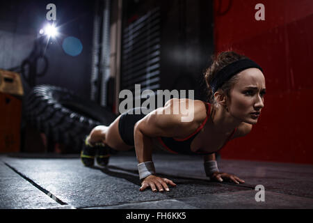Montare la donna facendo push-up in palestra Foto Stock