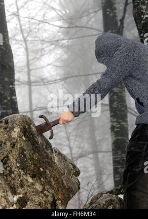 Valoroso cavaliere anonimo rimuove l'Excalibur magica spada nella roccia Foto Stock