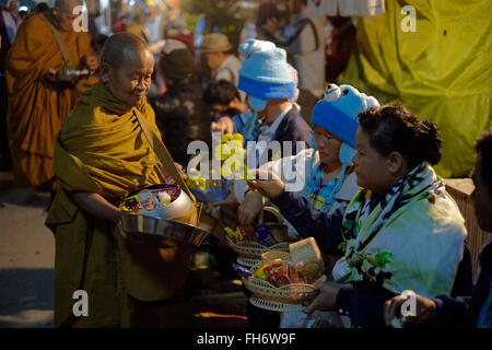 I monaci buddisti ricevendo alms dalla popolazione locale prima di prima luce su Chaikhong street, che nelle serate dei weekend si trasforma in una strada pedonale della città di Chiang Khan in Loei provincia situata nel nord-est della regione di Isaan sulla riva sud del fiume Mekong rivolta verso il Laos. Della Thailandia Foto Stock