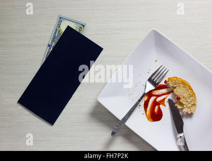 Piastra vuota a sinistra dopo la cena con Bill e Dollari nota sul tavolo di legno Foto Stock