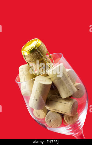 Bicchiere di vino con i tappi di sughero su sfondo rosso Foto Stock