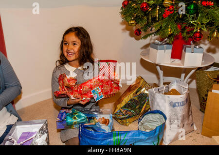 Una razza mista bambino aprendo i suoi regali di Natale Il giorno di Natale, Brighton, Sussex, Regno Unito Foto Stock