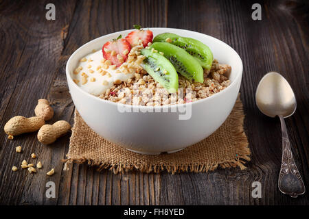 Una sana prima colazione, ciotola di muesli con yogurt e frutta fresca sul tavolo di legno Foto Stock