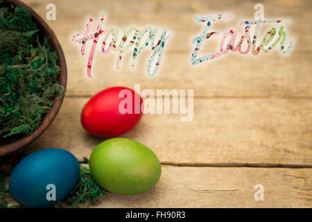 Tre uova colorate su una tavola di legno dello sfondo e del testo buona Pasqua Foto Stock