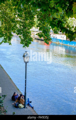 2 uomini che riposano sulla riva del fiume Ill, Strasburgo, Alsazia, Francia, Europa Foto Stock