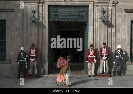 Una donna cammina davanti alla guardia del Palazzo Presidenziale di La Paz. Foto Stock