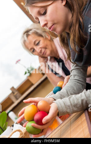 Madre e figlia con le uova di pasqua, seduti a un tavolo nella stanza vivente Foto Stock