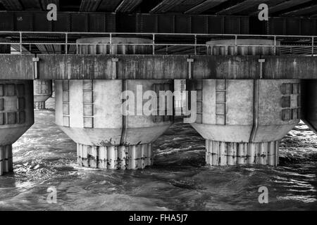 Ponte delle colonne di supporto che sorge fuori del fiume Foto Stock