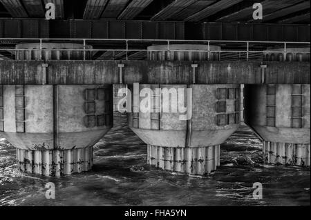 Ponte delle colonne di supporto che sorge fuori del fiume Foto Stock