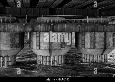 Ponte delle colonne di supporto che sorge fuori del fiume Foto Stock