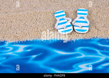 Giocattolo blu flip flop sul concetto di spiaggia con sabbia e lamina di acqua Foto Stock