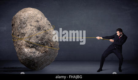 Imprenditore tirando enorme roccia con una corda Foto Stock