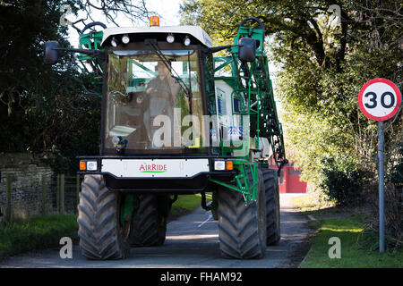 Un grande veicolo agricolo il riempimento di una stretta viuzza in un paese di campagna Foto Stock