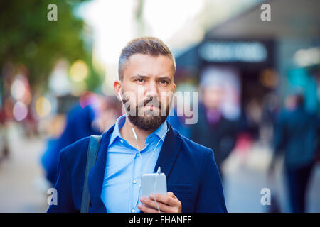 Manager con lo smartphone ascoltando musica fuori in strada Foto Stock