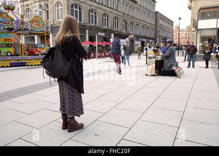 I giovani a Cardiff la visione di un musicista di strada a giocare il suo piano mobile. Febbraio 2016 Foto Stock