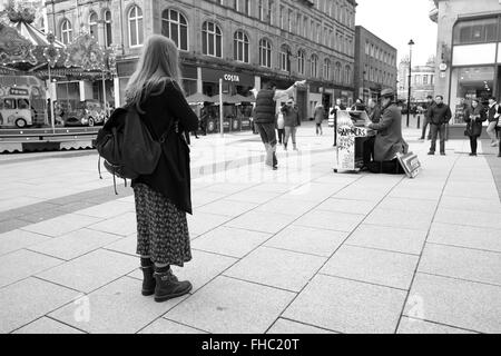 I giovani a Cardiff la visione di un musicista di strada a giocare il suo piano mobile. Febbraio 2016 Foto Stock