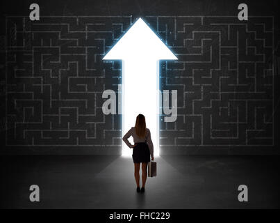 Persona d'affari guardando un labirinto con soluzione freccia sulla parete Foto Stock