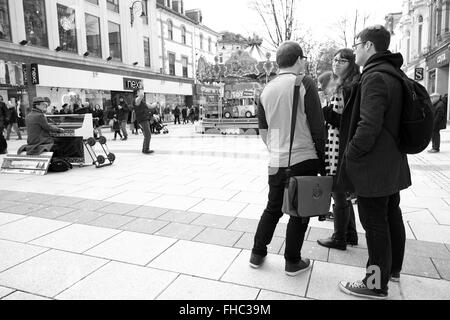 I giovani a Cardiff la visione di un musicista di strada a giocare il suo piano mobile. Febbraio 2016 Foto Stock