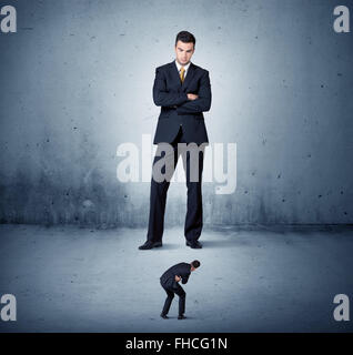 Arrabbiato enorme business man lokking al piccolo ragazzo Foto Stock