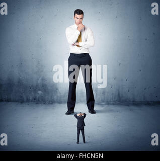 Arrabbiato enorme business man lokking al piccolo ragazzo Foto Stock