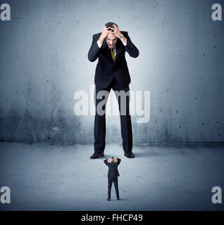 Arrabbiato enorme business man lokking al piccolo ragazzo Foto Stock