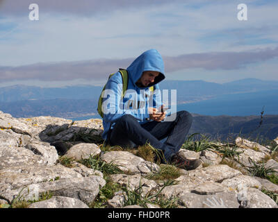 Giovane con appoggio mobile durante un sentiero escursionistico, della Sierra de Mijas, provincia di Malaga Costa del Sol. Andalusia Spagna meridionale Foto Stock