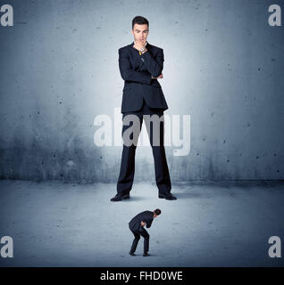 Arrabbiato enorme business man lokking al piccolo ragazzo Foto Stock