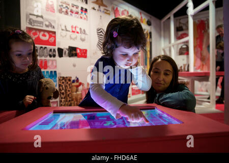 Milano, Italia. 24 Febbraio, 2016. Una bambina gioca un gioco per abbinare i vestiti e organizzare il guardaroba per Barbie alla mostra "barbie-l'icona' a Milano, in Italia, nel febbraio 24, 2016. La mostra resterà aperta fino al 13 marzo ed essere presente a Roma nel mese di aprile. Con 448 pezzi, la mostra è divisa in cinque tematiche, sezioni, tra "Barbie è la moda", "Barbie Famiglia", "Barbie CARRIERE', 'Dolls del Mondo' e 'celebrità', raccontando la storia di Barbie e i suoi effetti sulla moda, design, la vita di famiglia e di posti di lavoro per le donne. Credito: Jin Yu/Xinhua/Alamy Live News Foto Stock