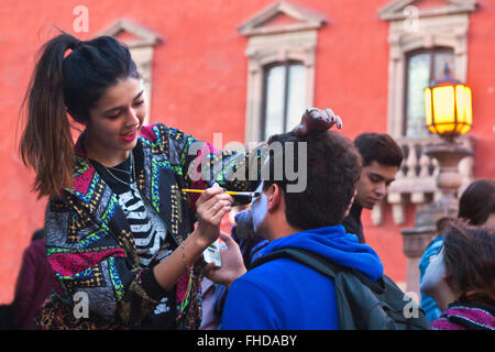 Le facce sono dipinte come teschi come le persone si trasformano in CATRINAS durante il giorno dei morti - San Miguel De Allende, MEX Foto Stock